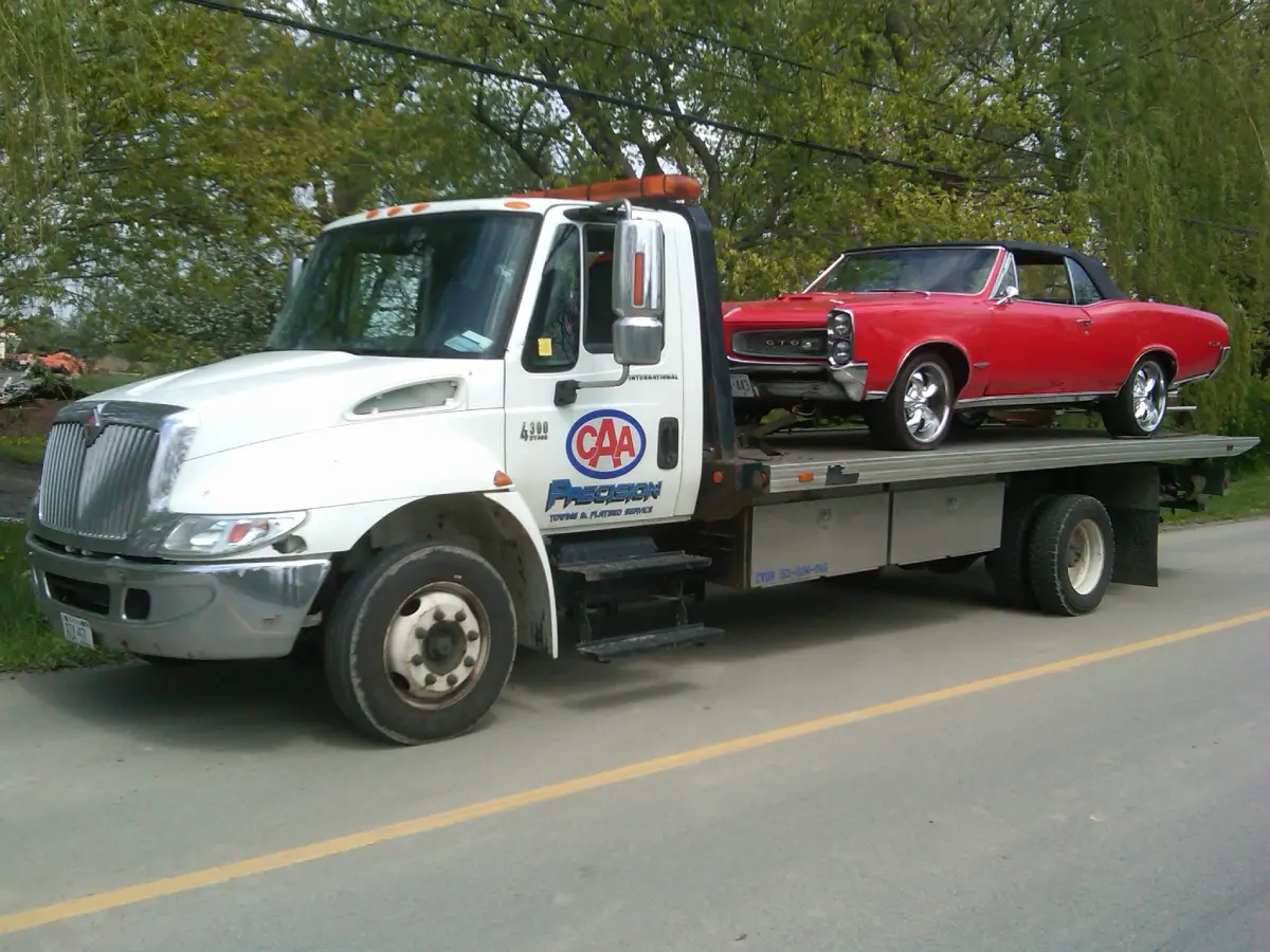 Towing truck carrying a red car